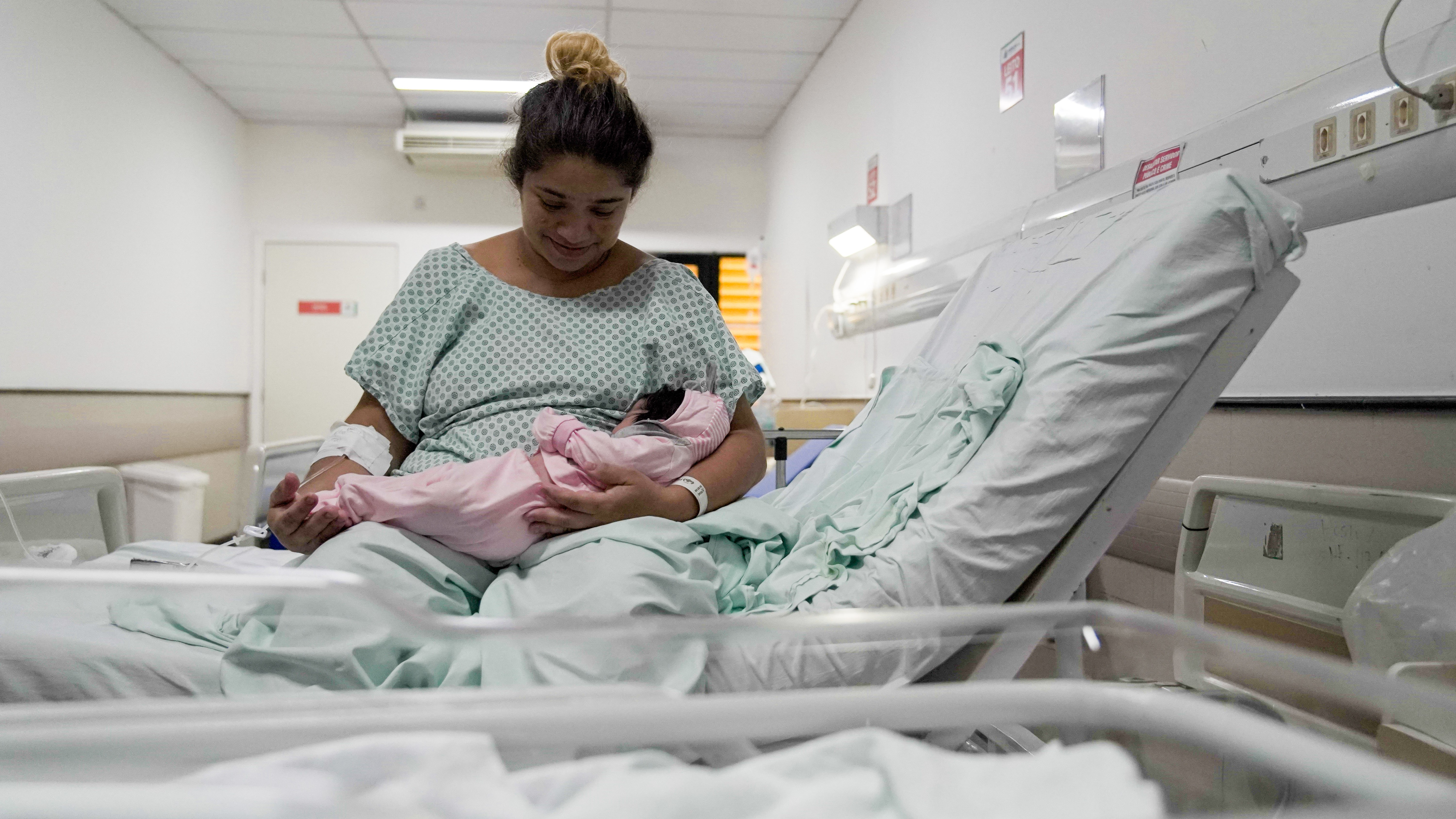 uma mulher com seu bebê num leito do hospital da mulher